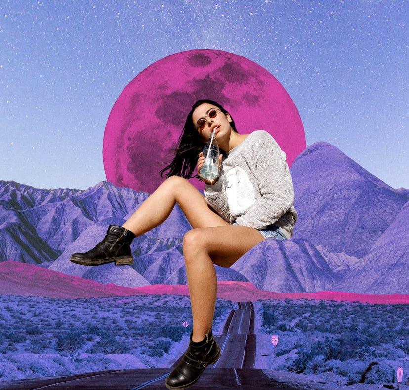 Young woman sipping a drink in front of a pink moon after reading her April 2023 horoscope.