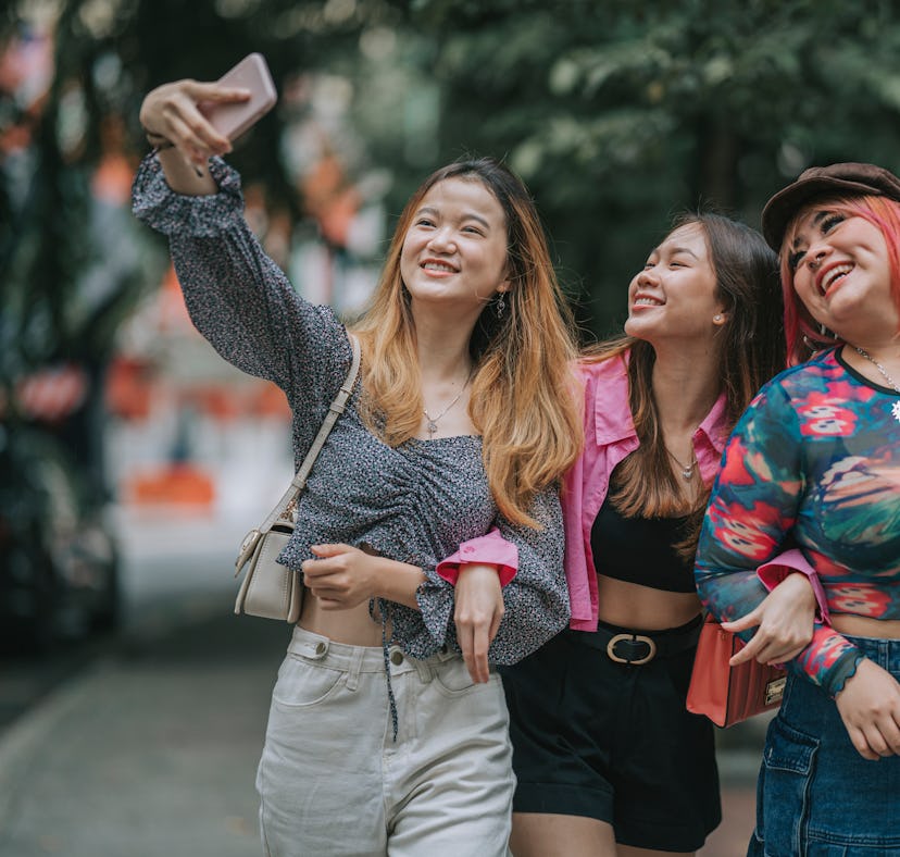 Three of the luckiest zodiac signs in April 2023 taking a selfie outside.