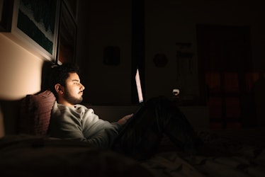 Man in bed at night looking at laptop 