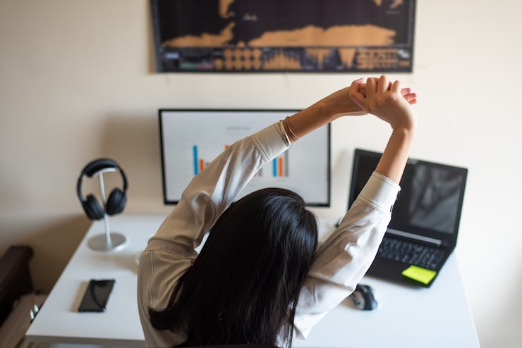 woman sitting and stretching at her desk