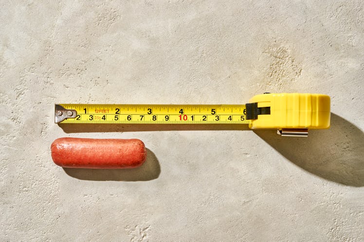 A measuring tape unrolled against a tiny sausage link.