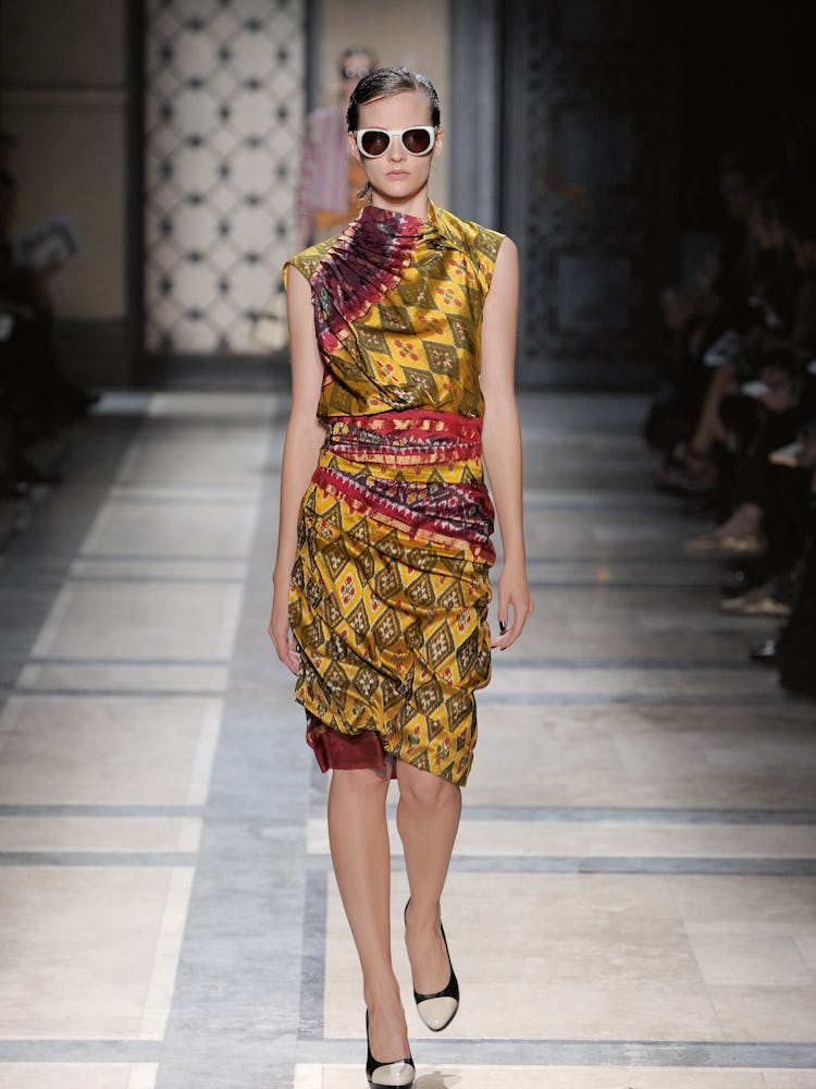 a model in a dries van noten runway show wears a sari-inspired ikat wrap dress