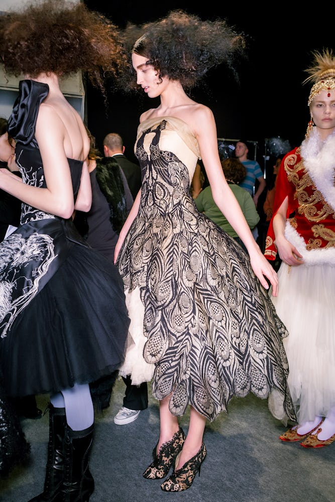 a model wearing a cream tulle evening dress with peacock lace appliqué during Alexander McQueen's fa...