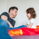 A father and child talking while sitting in bed.