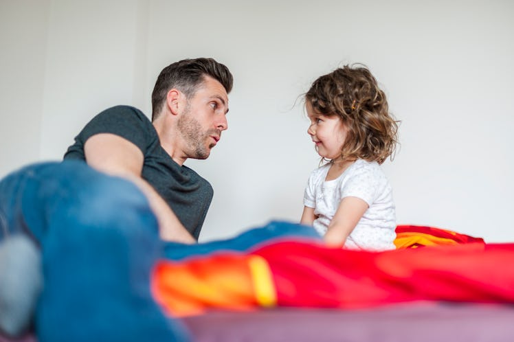 A father and child talking while sitting in bed.