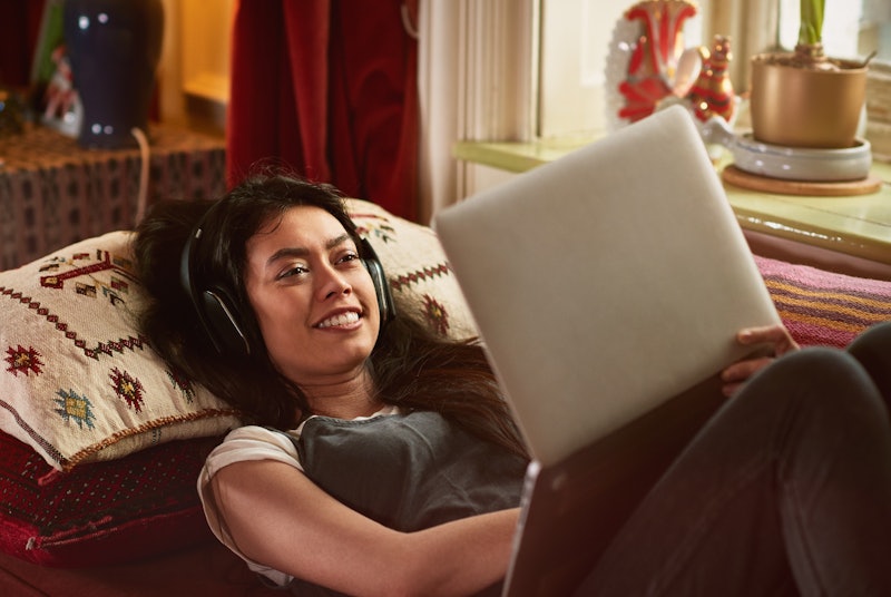 Stock image of a woman with headphones looking at a laptop