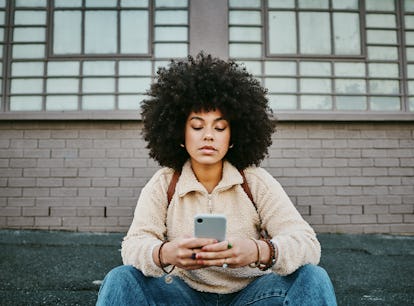 Young woman texting as one of the most emotionally distant zodiac signs.