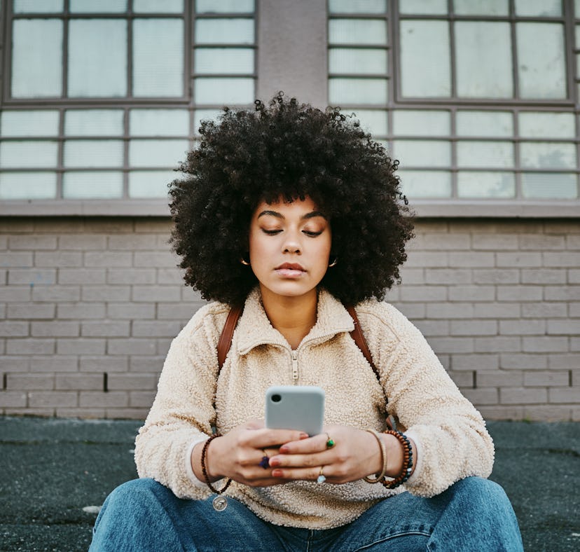 Young woman texting as one of the most emotionally distant zodiac signs.