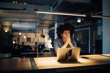 Man working in office at night looking frustrated and tired