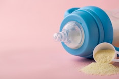 A baby bottle and a scoop of infant formula.