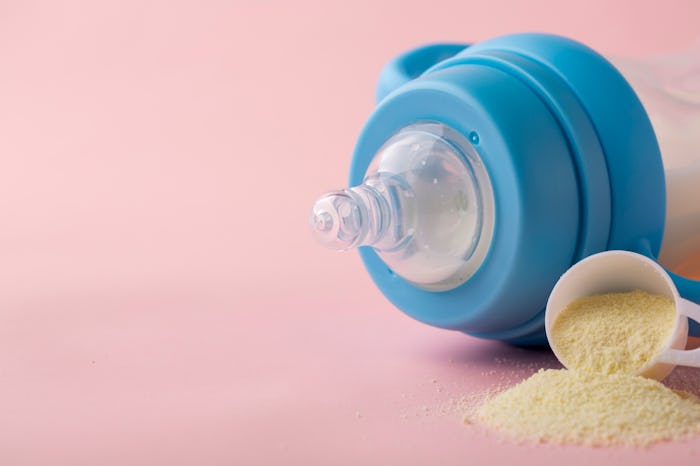 A baby bottle and a scoop of infant formula.