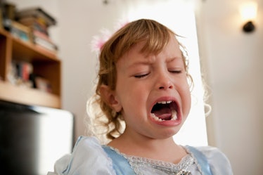A child in a princess dress cries and throws a tantrum.
