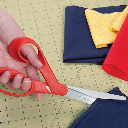 A left-handed person uses left handed scissors to cut fabric.