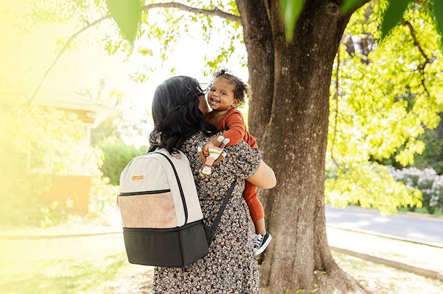 woman wearing backpack while holding toddler