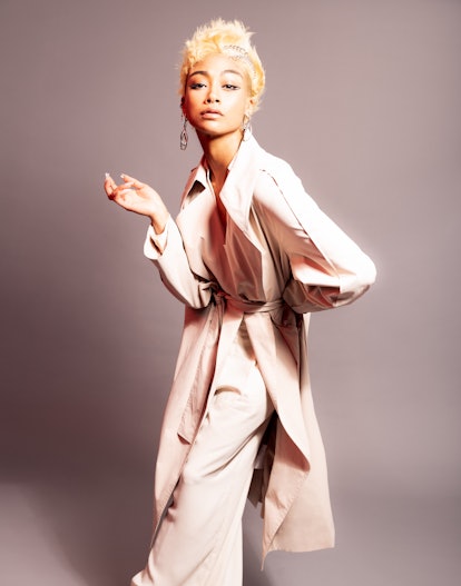 A portrait of Tati Gabrielle wearing a light pink trenchcoat