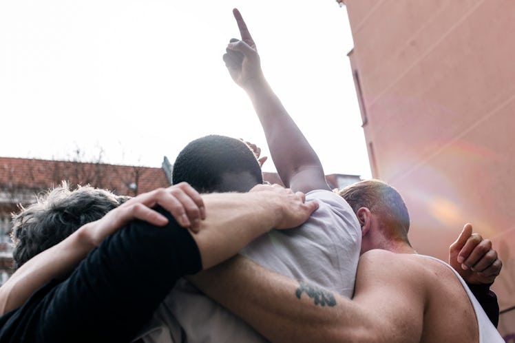 A group of men huddling, with one pointing his finger up in the air.