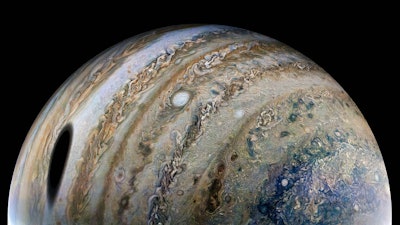 The icy moon Ganymede creates a round shadow over Jupiter's cloud tops. NASA's Juno spacecraft took ...