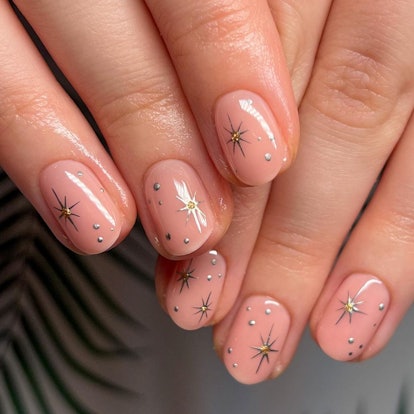 If you're going on a summer 2023 vacation, try nude nails with gold stars.