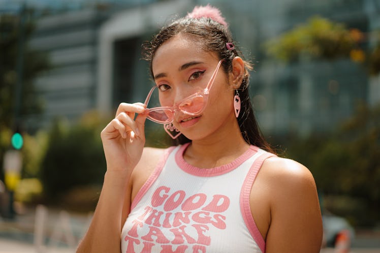 Young woman holding glasses outside during April 2023's hybrid solar eclipse, which has an interesti...