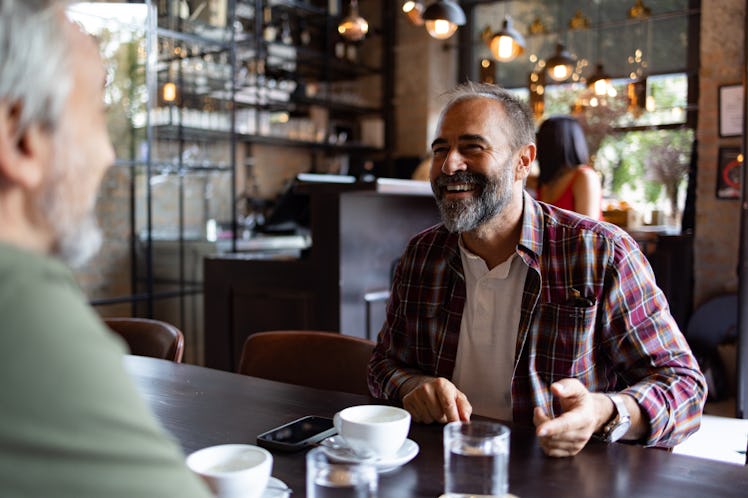 two adult male friends having happy conversation over coffee