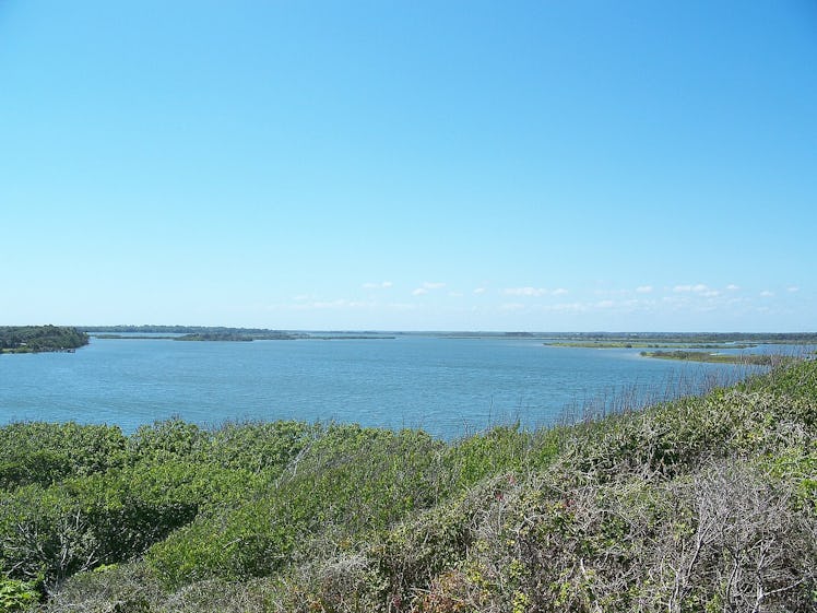 photo from a hilltop with green grass in foreground and blue water in distance