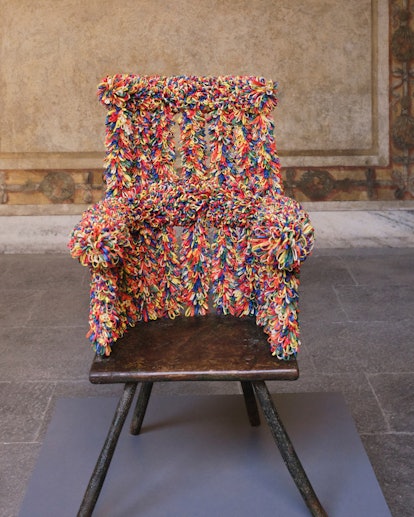 a wooden stick chair wrapped in rainbow yarn