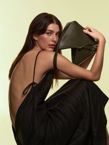 camilla morrone holding a brown leather handbag