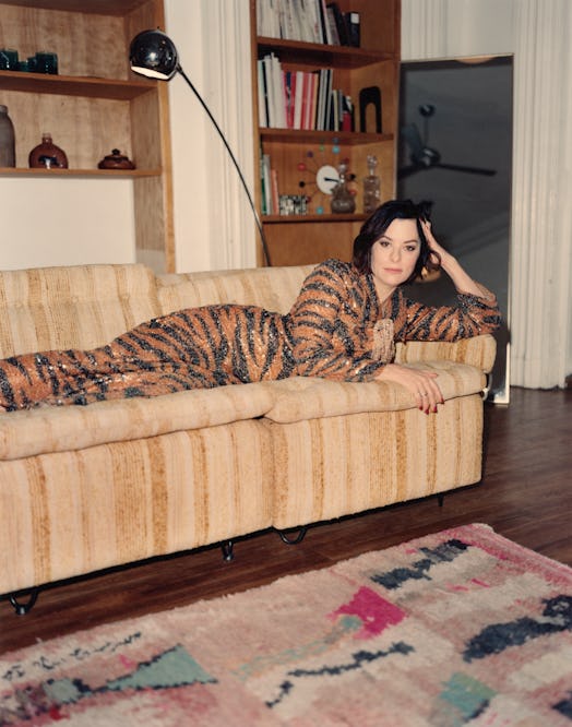 the actor Parker Posey lying on a couch in a tiger striped gown