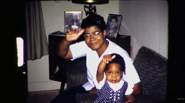 A mother and her daughter wave to a camera in a vintage photo.