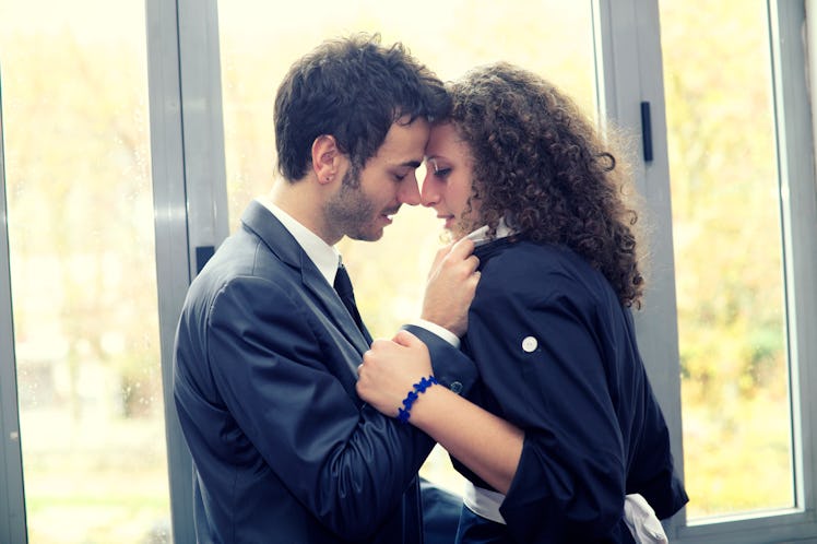 A man in a business suit kissing a woman.