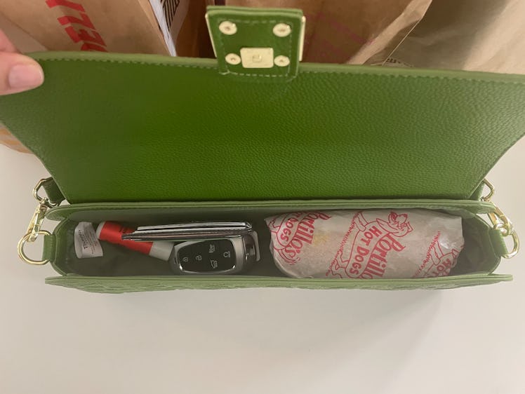 a view from the top of an open purse with a wrapped hot dog, keys, wallet, and lip balm inside