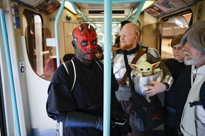 Fans dressed as Darth Maul and The Mandalorian with Grogu ride a train