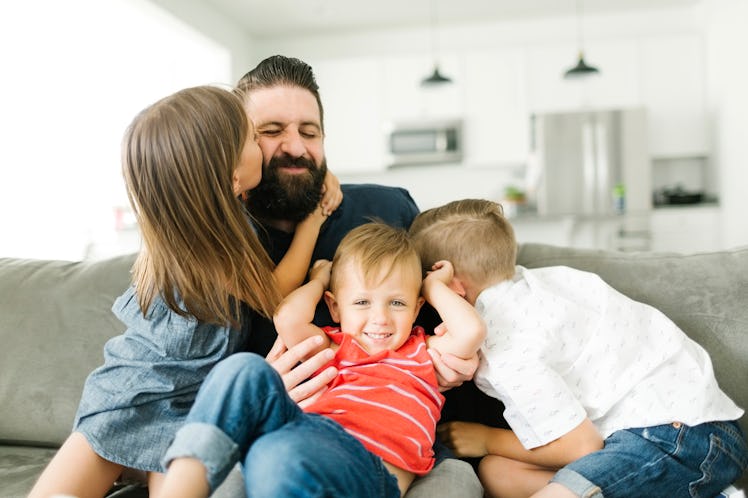Dad on couch with three children — two boys and a girl