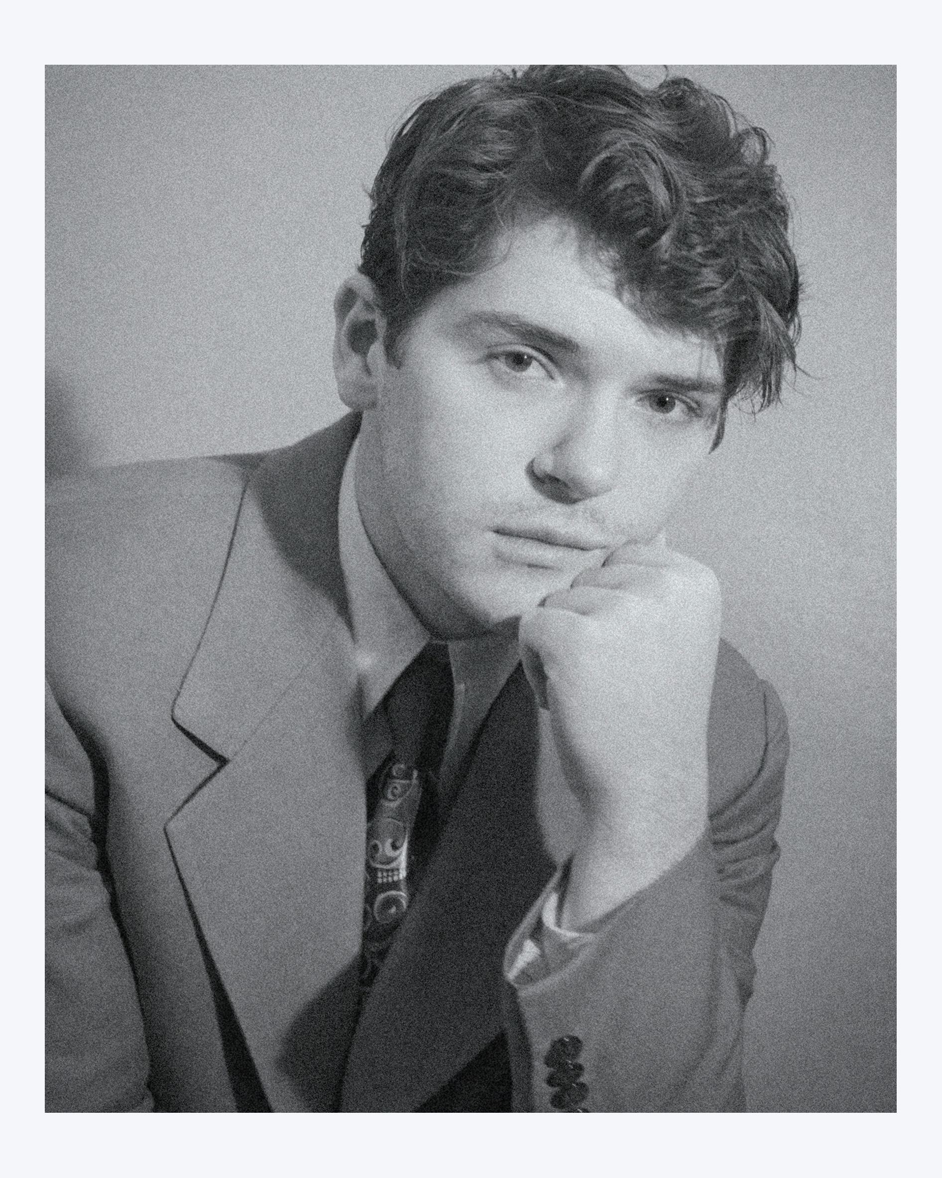 Colton Ryan staring pensively into the camera