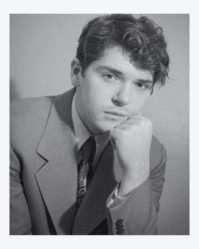 Colton Ryan staring pensively into the camera