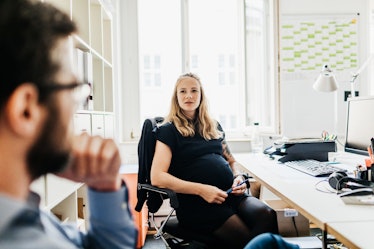 Pregnant woman at desk looking at man who's about to ask a question