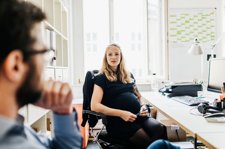 Pregnant woman at desk looking at man who's about to ask a question