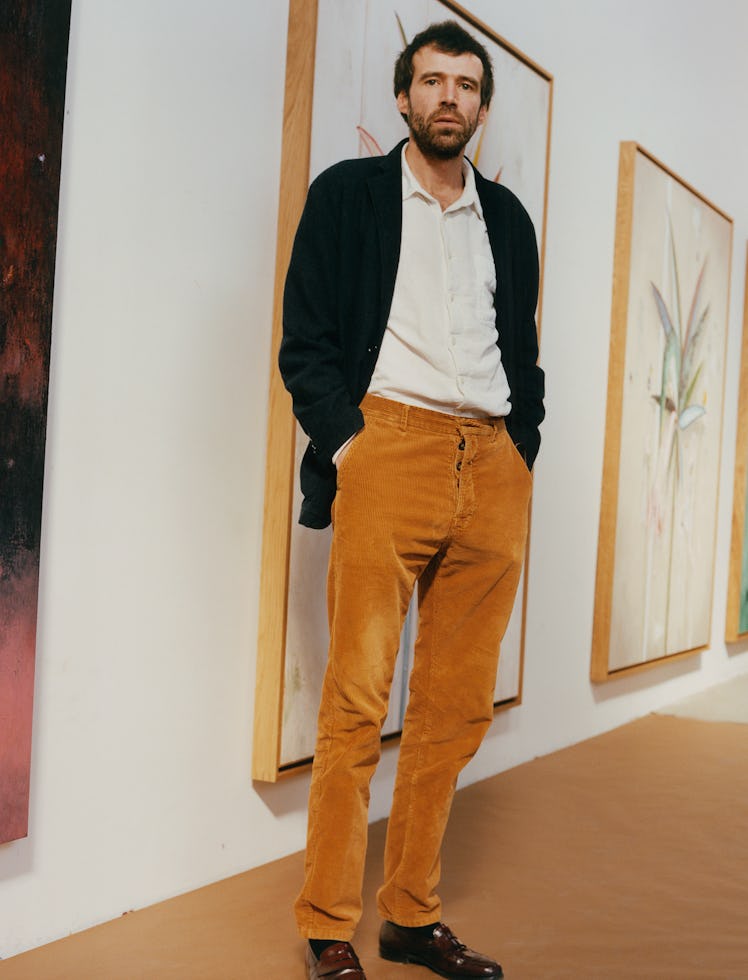 Harold Ancart in his studio in Brooklyn, with an untitled painting from 2022 (right). Ancart wears h...