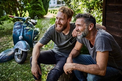 Middle-aged friends smiling and laughing beside scooter