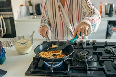 A woman cooking pancakes on a gas stove.
