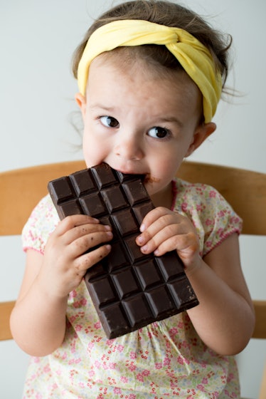 A toddler eating a dark chocolate bar.