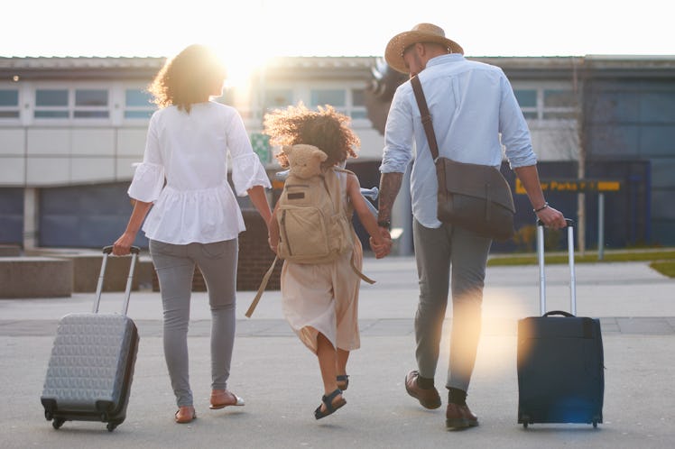 Family of three rolling luggage through airport