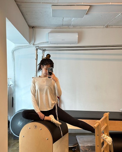 Jennie from BLACKPINK does a seated side bend during her Pilates routine. 
