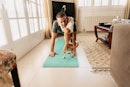 一个男人独自在客厅里做瑜伽，他的狗跳起来吻他。