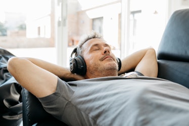A man wearing headphones while reclining, listening to binaural beats.