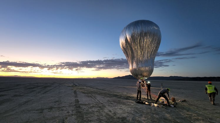 A peanut-shaped, shiny balloon with the setting sun in the background