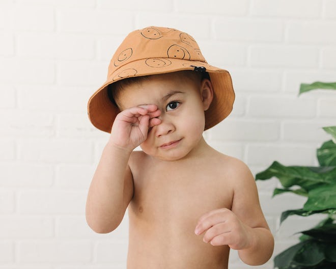 A bucket hat with smiley faces on it, perfect for matching baby swimsuits.