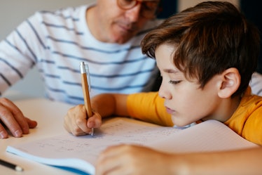 A dad helps his son do homework.