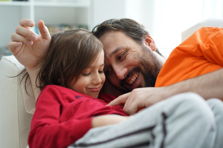 A dad talking to his child, smiling on a couch.