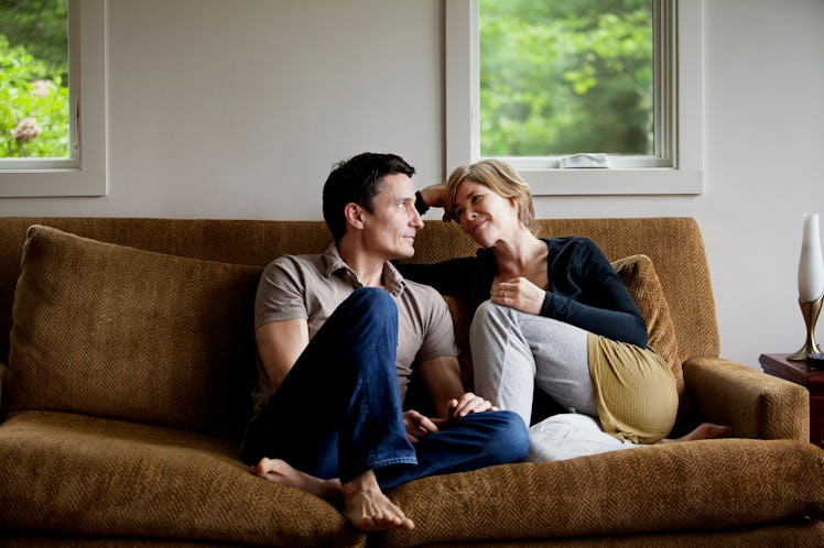 husband and wife sitting on couch talking intimately